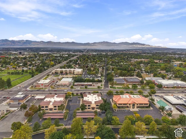 Aerial perspective of a multi-building commercial complex featuring asphalt parking lots, covered parking structures, and mountain backdrop