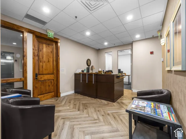 Reception area featuring herringbone-patterned wood-finish flooring, built-in dark wood reception desk, and solid wood-trimmed door