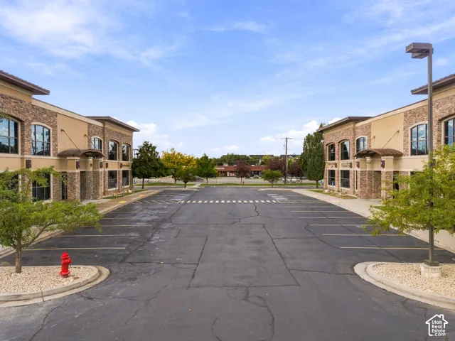 Commercial complex exterior featuring stone veneer facade, arched window detailing, professional landscaping, and dedicated asphalt parking area
