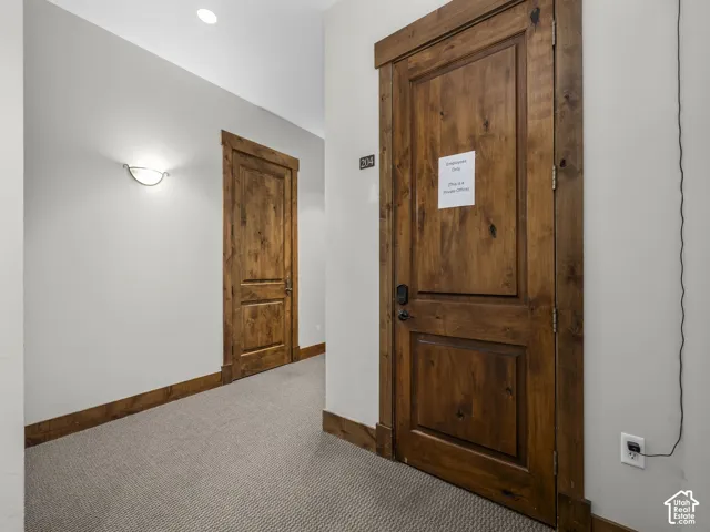 Solid wood interior doors with matching trim, textured wall-to-wall carpeting, and wall-mounted sconce lighting