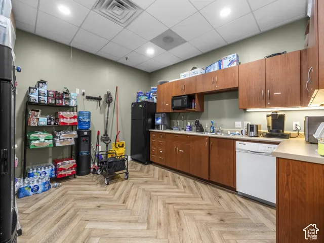 Kitchenette featuring wood-finish cabinetry, solid-surface countertops, recessed lighting, drop ceiling, and herringbone-pattern wood-finish flooring