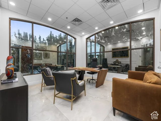 Expansive floor-to-ceiling windows with bronze-finish frames, stone-finish tile flooring, and recessed ceiling lighting