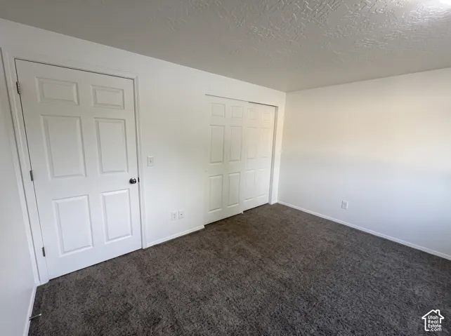 Interior room featuring neutral wall-to-wall carpeting, white six-panel swing door, and white sliding closet doors