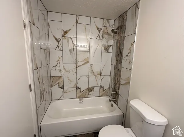 Bathtub featuring floor-to-ceiling large-format porcelain tile surround with a marble-finish pattern and a vertical glass-tile accent inlay