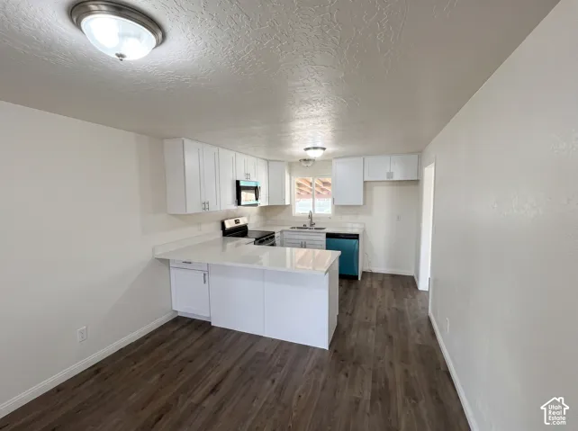 Kitchen featuring white cabinetry, quartz countertops, wood-finish flooring, a stainless steel sink, and integrated overhead lighting