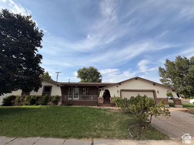Single-story residence featuring a multi-material exterior of masonry and stucco, an integrated two-car garage, covered porch with decorative metal railing, and arched architectural detailing