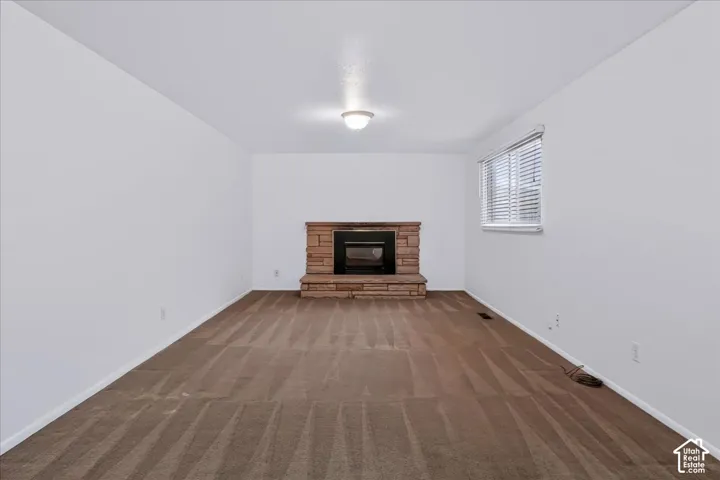 Stone-finish fireplace surround with an integrated firebox, neutral carpeting, and horizontal window blinds