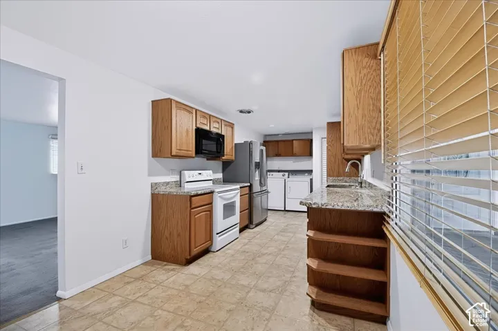 Kitchen featuring wood cabinetry, stone-patterned countertops, tile flooring, and integrated laundry area