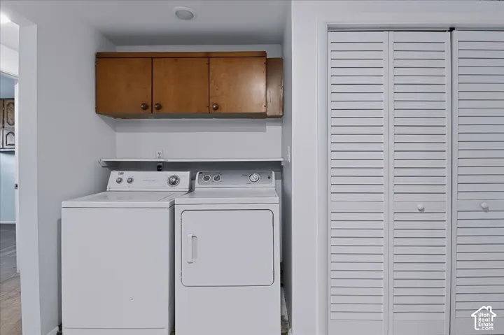 Laundry area featuring wall-mounted wood cabinetry, a built-in shelving unit, and louvered bifold closet doors