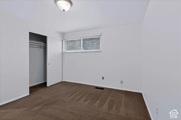 Interior space featuring wall-to-wall carpeting, a sliding-door closet, a horizontal window with adjustable blinds, and a central ceiling-mounted light fixture