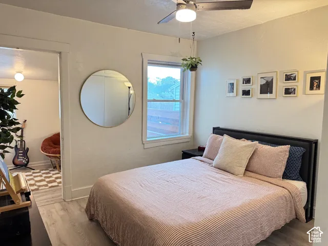 Light-filled room featuring wood-finish flooring, a ceiling fan with integrated lighting, and a sash window
