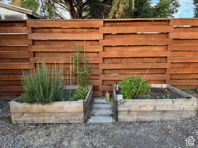 Horizontal-slat wood privacy fencing paired with two raised timber garden beds and gravel ground covering