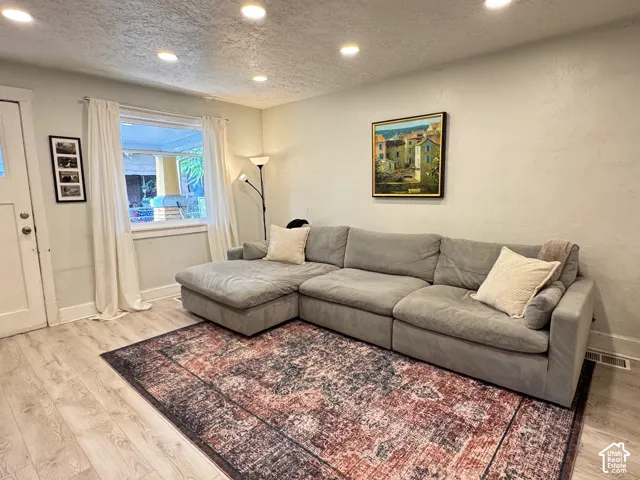 Neutral-toned living space featuring recessed lighting and wood-finish flooring