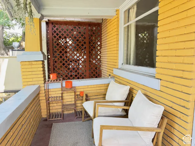 Covered porch featuring yellow brick masonry, wooden lattice privacy screen, and wide concrete capped perimeter walls