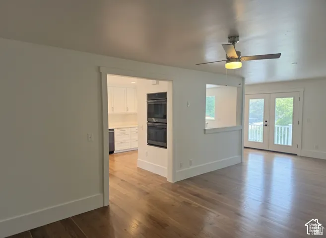 Interior space featuring wood-finish flooring, white cabinetry, a built-in double oven, and double French doors with glass panes