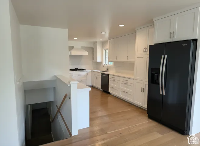 Kitchen featuring white shaker-style cabinetry, wood-finish flooring, recessed lighting, and a custom range hood