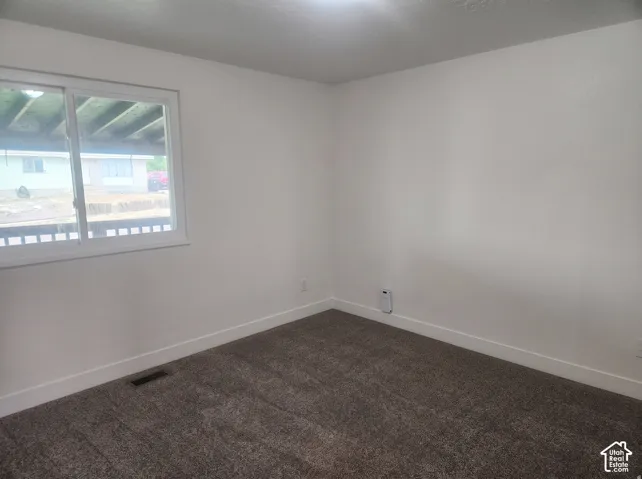 Neutral-toned wall paint, gray wall-to-wall carpeting, and a wide sliding window