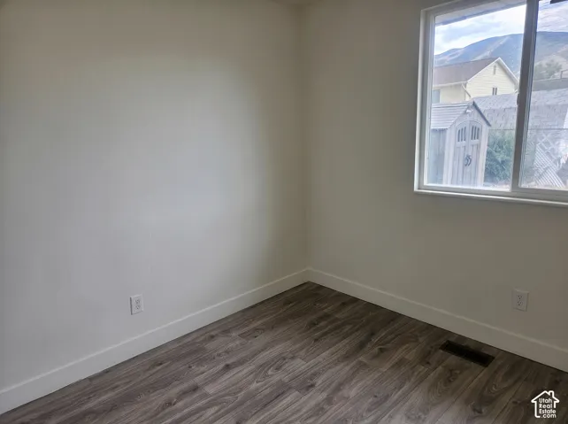 Room featuring wood-finish flooring, neutral wall tones, and a large window with mountain scenery