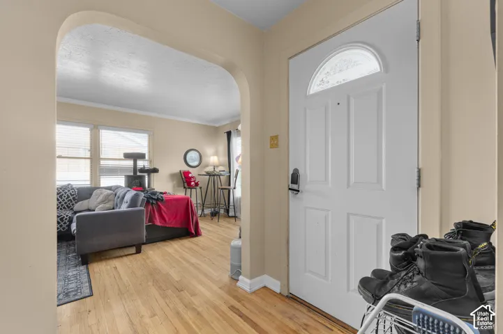 Entryway featuring wood-finish flooring, an arched doorway, and an exterior door with a semi-circular transom window