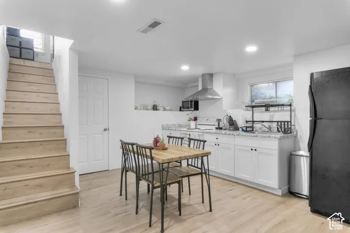 Kitchen featuring white shaker-style cabinetry, stone-finish countertops, stainless steel range hood, recessed lighting, and wood-finish flooring