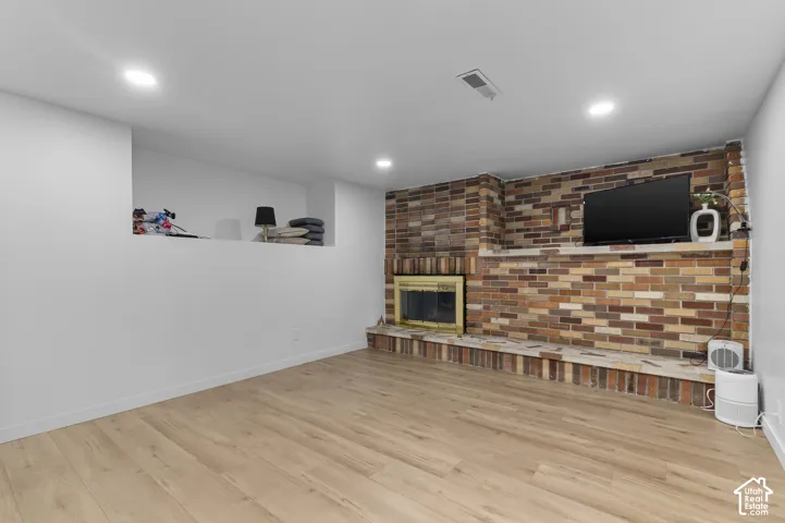 Multi-tonal brick fireplace featuring a raised hearth and integrated display alcove, complemented by wood-finish flooring and recessed lighting