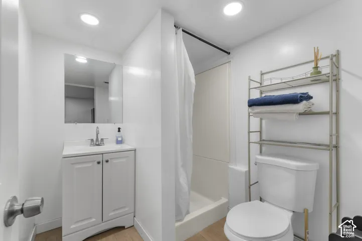 Bathroom featuring a white vanity cabinet with a stone-surface countertop, recessed lighting, wall-mounted mirror, and a tub-shower combination with a surround finish