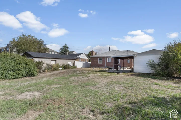 Spacious backyard featuring a brick exterior residence, a covered patio, and a detached garage