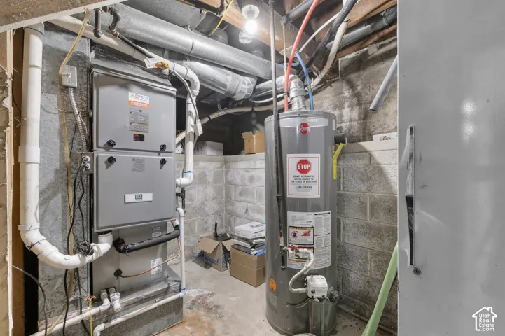 Mechanical area featuring a Newer high-efficiency furnace, tank-style water heater, and exposed concrete block foundation walls