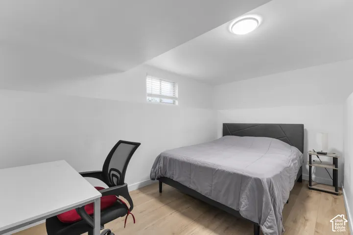 Room featuring wood-finish flooring, white walls, and a recessed ceiling light fixture with a window featuring horizontal blinds
