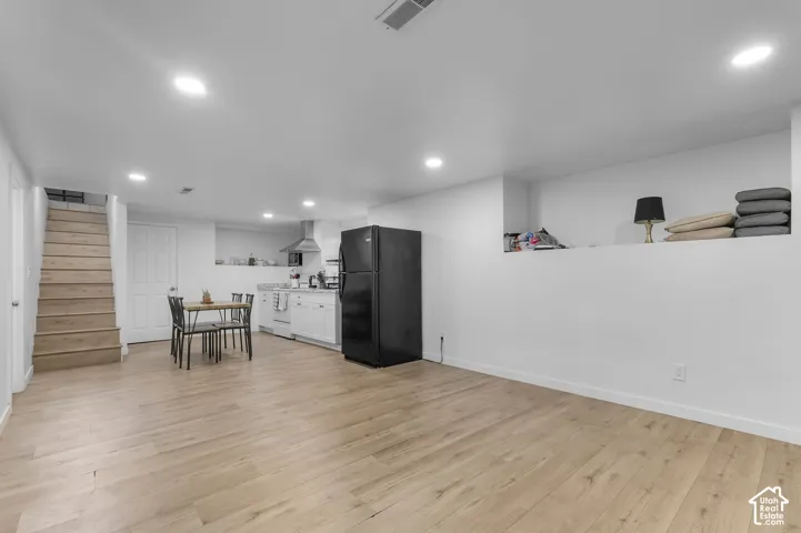 Open-concept interior featuring wood-finish flooring, recessed lighting, white cabinetry, a built-in recessed storage niche, and wood-tread stairs