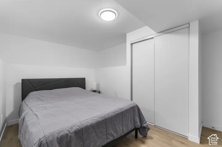 Neutral-toned room featuring wood-finish flooring, a sliding-door closet, and a flush-mount overhead light fixture