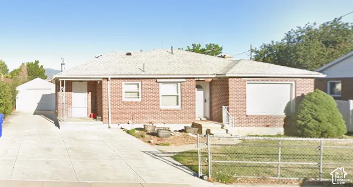 Red brick exterior featuring a covered front porch, concrete driveway, and detached garage