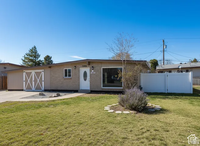 Single-story exterior featuring a brick facade, attached garage with decorative cross-buck doors, and a white privacy fence