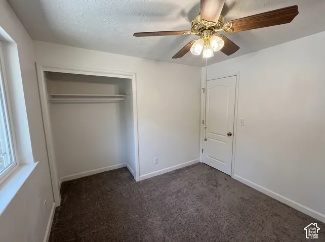 Neutral-toned carpeting, ceiling fan with integrated light fixture, built-in closet shelving, and a paneled interior door