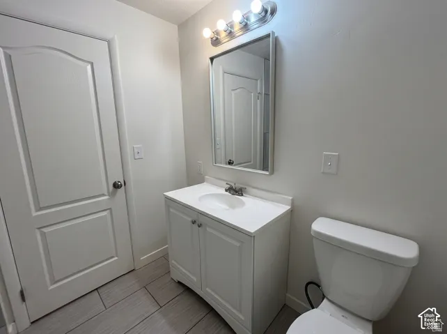 Bathroom featuring tile flooring, a white vanity with an integrated sink, a rectangular mirror, and a four-light fixture