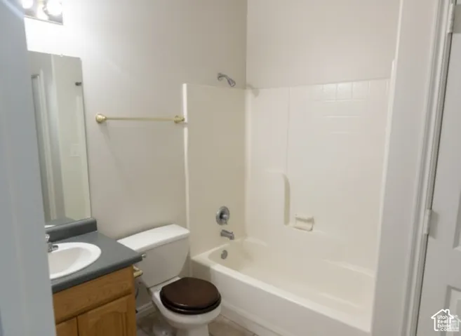 Bathroom featuring a composite shower and tub surround, wood-finish cabinetry, a solid-surface countertop with an integrated basin, and a wall-mounted vanity mirror