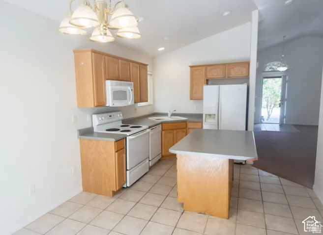 Kitchen featuring oak-finish cabinetry, neutral solid-surface countertops, central island, tiled flooring, and vaulted ceilings