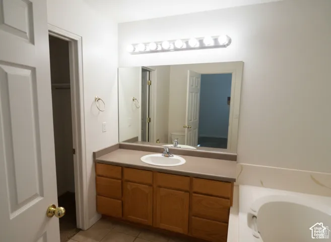 Wood-finish vanity cabinetry with a solid surface countertop, oval drop-in sink, large wall-mounted mirror, and multi-bulb light fixture