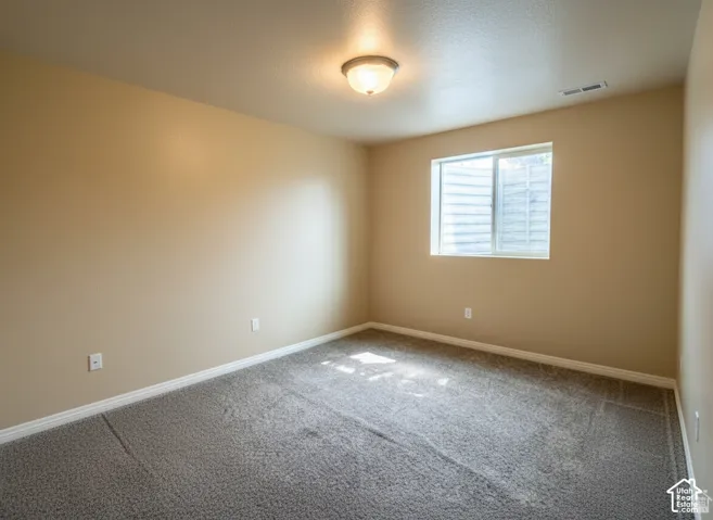 Interior space featuring neutral wall paint, wall-to-wall carpeting, a flush-mount ceiling light fixture, and a sliding window with an integrated window well
