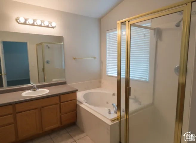 Vanity featuring wood cabinetry and a solid-surface countertop with an integrated basin, accompanied by a jetted soaking tub, a separate walk-in shower with a metal frame, and a wall-mounted light fixture