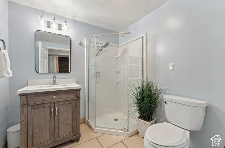 Bathroom featuring a wood-finish vanity with a white countertop, a corner shower with glass enclosure, a rectangular mirror with a black frame, and a three-light vanity fixture