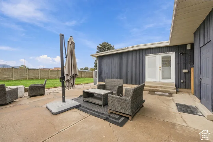 Concrete patio featuring vertical siding, double glass-pane doors, and a decorative block privacy wall