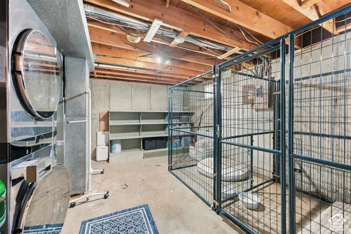 Utility area featuring exposed timber ceiling joists, concrete foundation walls, built-in open shelving, and modular metal enclosures