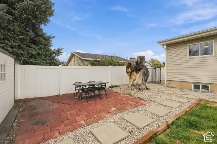 Backyard featuring a red paver patio, decorative gravel landscape, concrete paver path, vinyl privacy fencing, and exterior vinyl siding