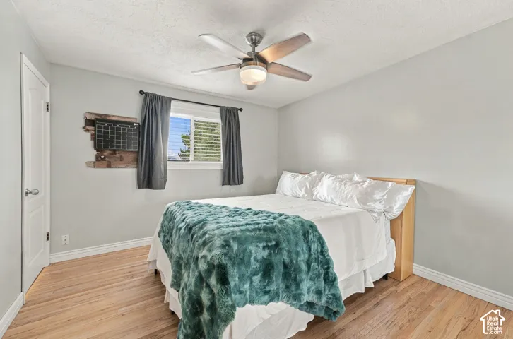 Interior space featuring wood-finish flooring, a neutral wall palette, a ceiling fan with integrated lighting, and a slider window