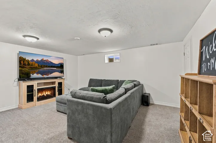Neutral-toned interior room featuring wall-to-wall carpeting, an integrated fireplace console with built-in cabinetry, and dual flush-mount ceiling light fixtures