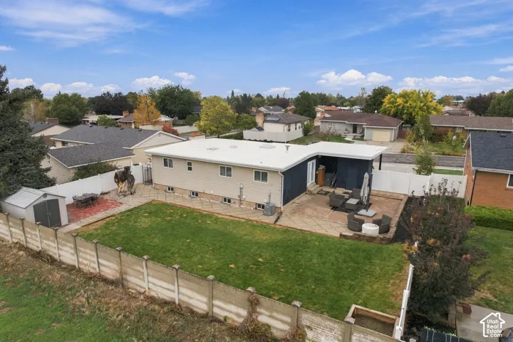 Exterior featuring a flat roof, large paved patio, fenced backyard, and a detached storage shed