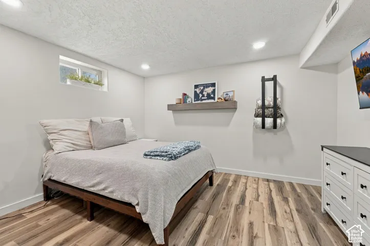 Neutral-toned room featuring wood-finish flooring, recessed lighting, and a wall-mounted wood-finish floating shelf