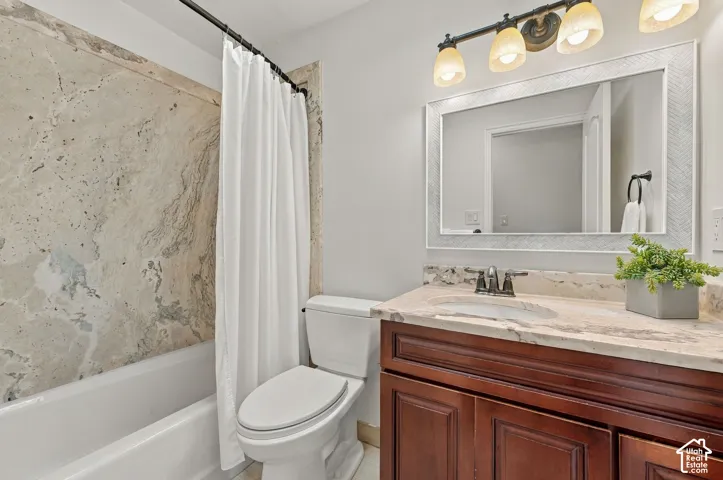 Vanity featuring a stone-surface countertop with an integrated oval sink and dark wood-finish cabinetry, complemented by a stone-tiled shower surround, a framed wall mirror, and multi-bulb overhead lighting