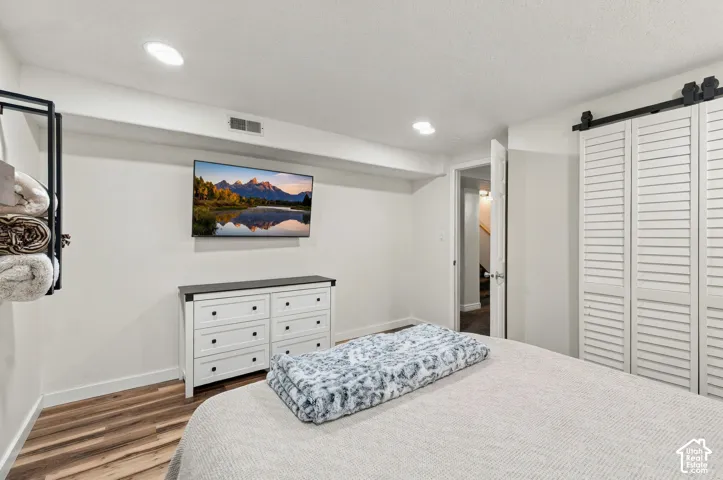 Recessed lighting, wood-finish flooring, and white louvered barn-style closet doors